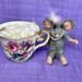 Mouse sits beside pretty little cup